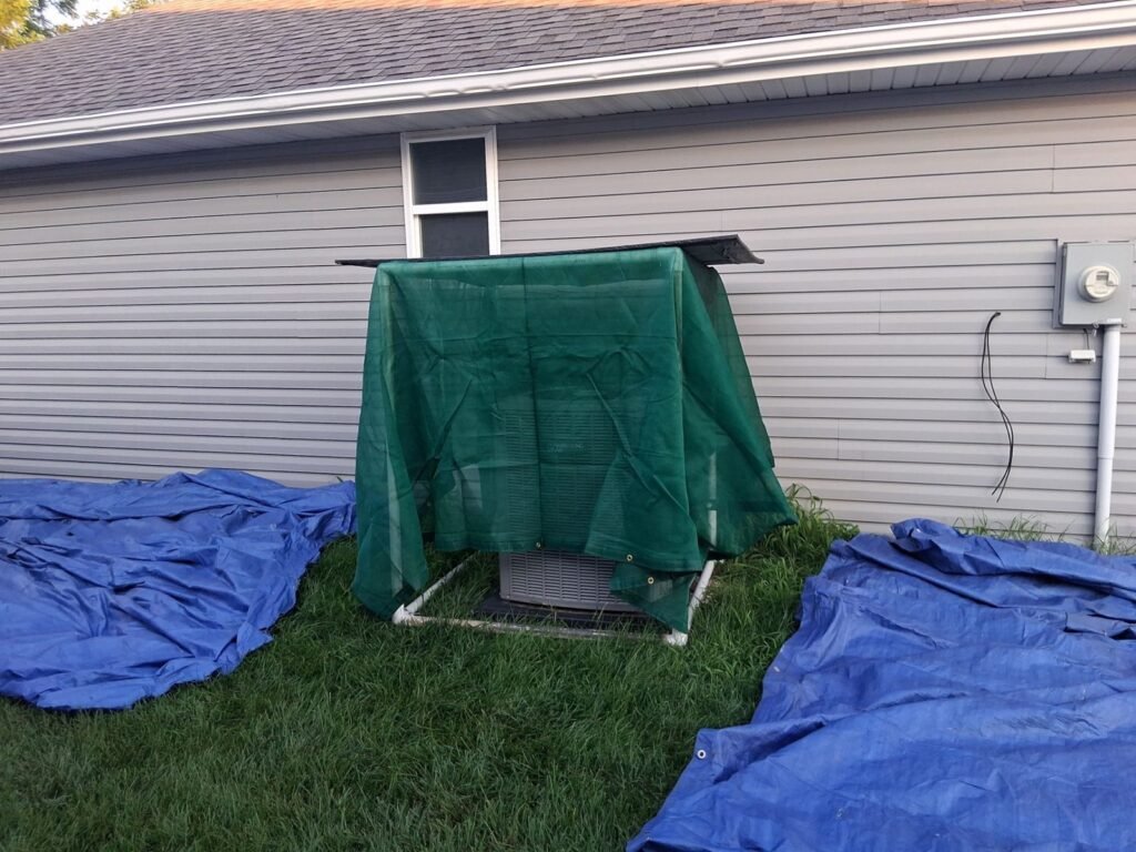 Bold Roofing crew protecting an AC unit and lawn with tarps during a Springfield, MO roof replacement