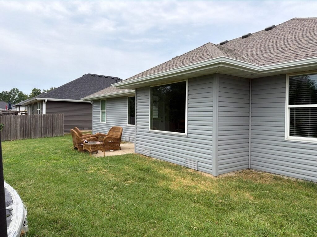 Rear of a Springfield, MO home with new vinyl siding and gutters after hail damage repairs