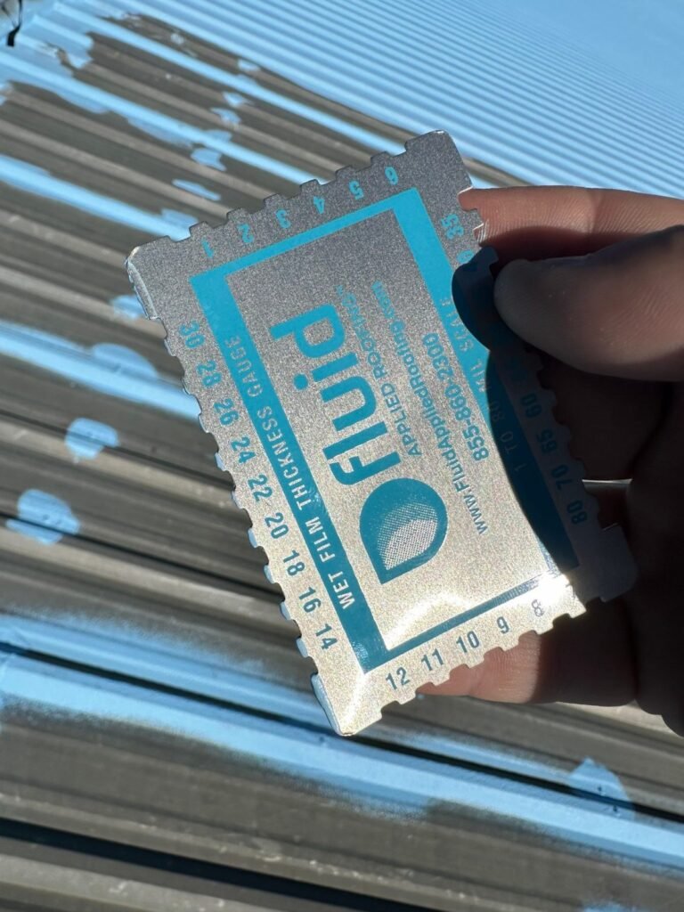 Wet film thickness gauge checking coating thickness during a commercial roof restoration